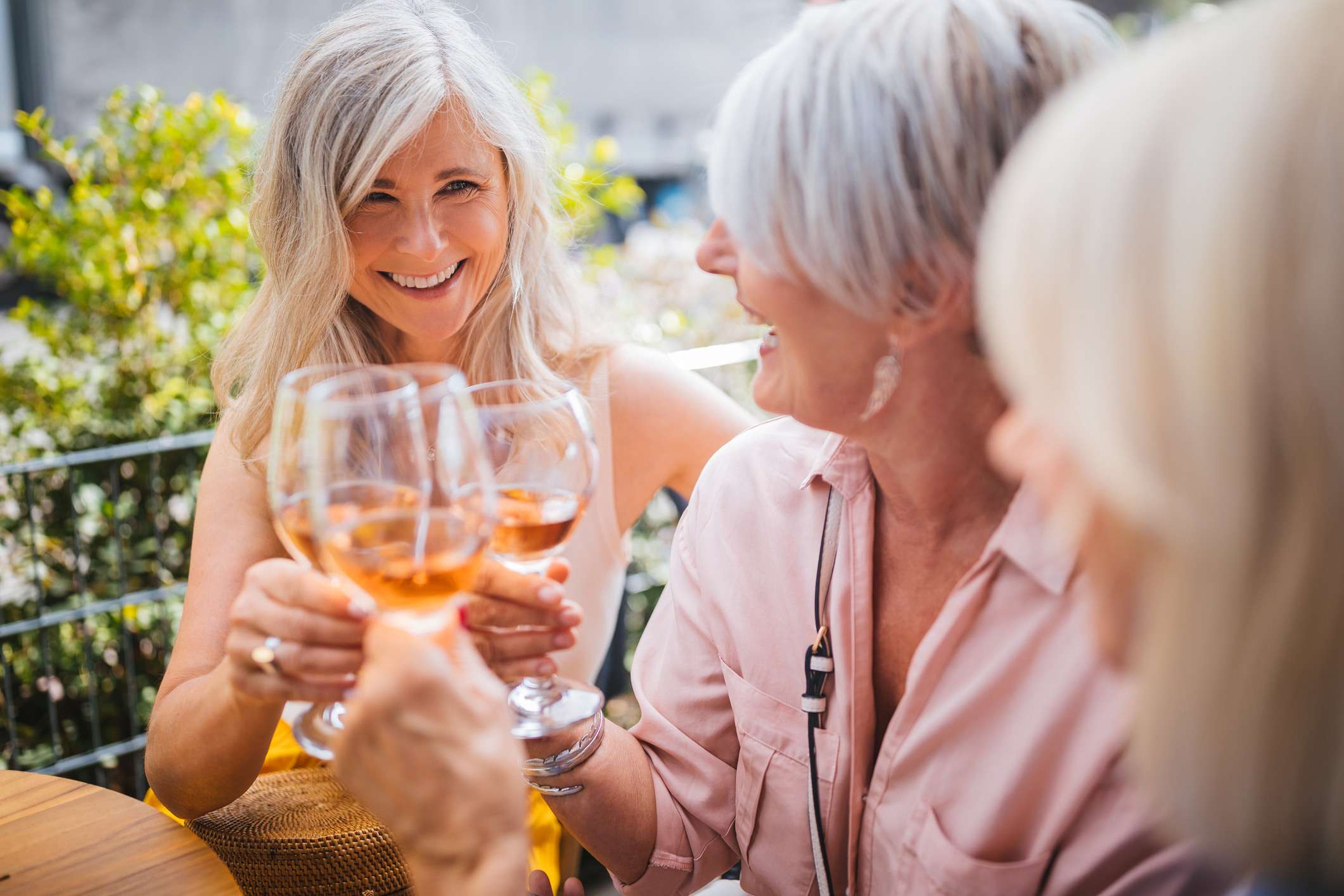 Fashionable mature women having fun toasting and drinking wine